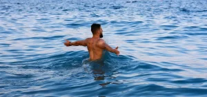 Fitness Coach beim Schwimmen im Meer - Regeneration im Personal Training Online